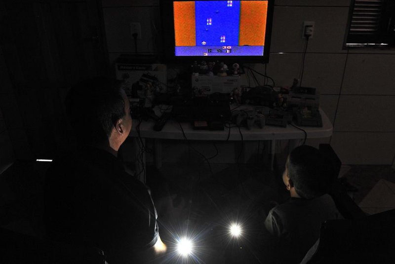  Santa Maria, , Brasil, 22/04/2017.Videogame Atari, entre outros, estão sendo relançados. Tem quem goste da versão atual e quem prefira comprar os clássicos dos anos 1980.Na foto: Deivid Gomes e o filho Nicolas, em casa jogando Atari.Indexador: GERMANO RORATO
