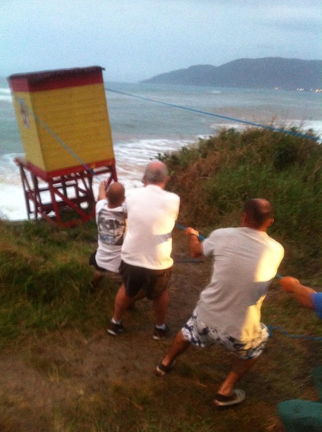 Moradores tentam resgatar um posto de salva-vidas que está caindo na praia do caldeirão no sul da ilha Moradores tentam resgatar um posto de salva-vidas que está caindo na praia do caldeirão no sul da ilha