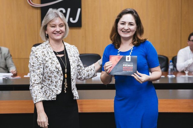 HomenagemHá oito anos, a Acij criou o Prêmio Núcleo Referência, que busca dar destaque aos trabalhos apresentados na entidade. Na foto, um registro do momento em que a diretora de relacionamento com o associado, Tina Marcato (E), faz a entrega para Carla Pinheiro, presidente do Conselho dos Núcleos, do primeiro exemplar do Caderno de Cases ¿ Prêmio Núcleo Referência 2017. HomenagemHá oito anos, a Acij criou o Prêmio Núcleo Referência, que busca dar destaque aos trabalhos apresentados na entidade. Na foto, um registro do momento em que a diretora de relacionamento com o associado, Tina Marcato (E), faz a entrega para Carla Pinheiro, presidente do Conselho dos Núcleos, do primeiro exemplar do Caderno de Cases ¿ Prêmio Núcleo Referência 2017.