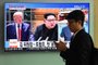 A man walks past a television news screen showing US President Donald Trump (L) and North Korean leader Kim Jong Un (C), at a train station in Seoul on June 11, 2018.Kim Jong Un and Donald Trump will meet on June 12 for an unprecedented summit in an attempt to address the last festering legacy of the Cold War, with the US President calling it a one time shot at peace. / AFP PHOTO / Jung Yeon-je