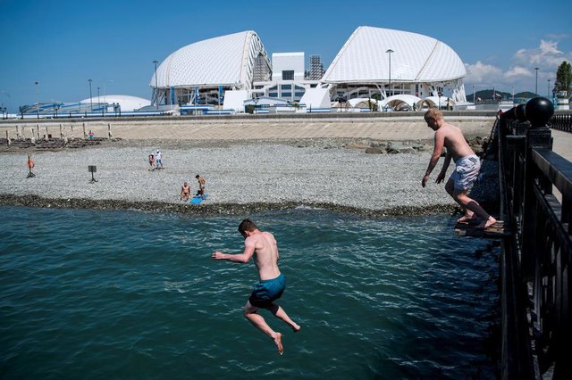 People jump off a jetty near the Fisht Olympic Stadium on June 8, 2018 ahead of the Russia 2018 World Cup in Sochi, Russia. / AFP PHOTO / Jonathan NACKSTRAND People jump off a jetty near the Fisht Olympic Stadium on June 8, 2018 ahead of the Russia 2018 World Cup in Sochi, Russia. / AFP PHOTO / Jonathan NACKSTRAND