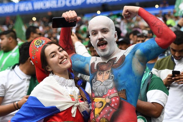Russia fans pose as they wait for the start of the Russia 2018 World Cup Group A football match between Russia and Saudi Arabia at the Luzhniki Stadium in Moscow on June 14, 2018. / AFP PHOTO / Patrik STOLLARZ / RESTRICTED TO EDITORIAL USE - NO MOBILE PUSH ALERTS/DOWNLOADS Russia fans pose as they wait for the start of the Russia 2018 World Cup Group A football match between Russia and Saudi Arabia at the Luzhniki Stadium in Moscow on June 14, 2018. / AFP PHOTO / Patrik STOLLARZ / RESTRICTED TO EDITORIAL USE - NO MOBILE PUSH ALERTS/DOWNLOADS