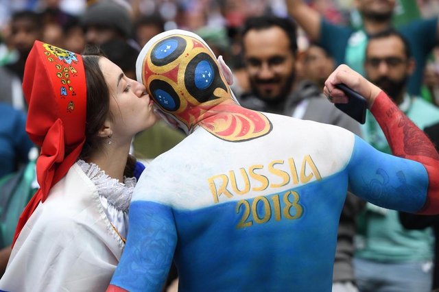 A Russia fan kisses another supporter before the start of the Russia 2018 World Cup Group A football match between Russia and Saudi Arabia at the Luzhniki Stadium in Moscow on June 14, 2018. / AFP PHOTO / Patrik STOLLARZ / RESTRICTED TO EDITORIAL USE - NO MOBILE PUSH ALERTS/DOWNLOADSEditoria: SPOLocal: MoscowIndexador: PATRIK STOLLARZSecao: soccerFonte: AFPFotógrafo: STR A Russia fan kisses another supporter before the start of the Russia 2018 World Cup Group A football match between Russia and Saudi Arabia at the Luzhniki Stadium in Moscow on June 14, 2018. / AFP PHOTO / Patrik STOLLARZ / RESTRICTED TO EDITORIAL USE - NO MOBILE PUSH ALERTS/DOWNLOADSEditoria: SPOLocal: MoscowIndexador: PATRIK STOLLARZSecao: soccerFonte: AFPFotógrafo: STR