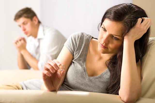 mulher triste olhanda aliança com homem ao fundo mulher triste olhanda aliança com homem ao fundo