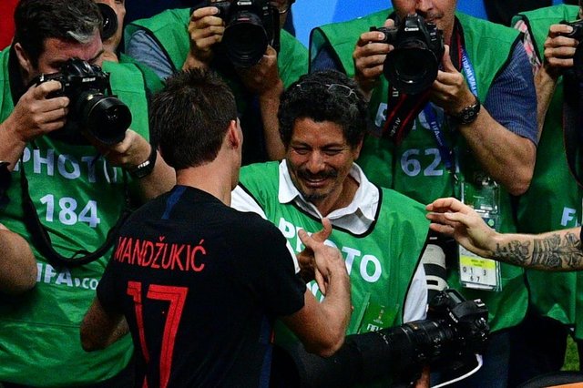 Croatias forward Mario Mandzukic (L) shakes hands with AFP photographer Yuri Cortez (C) after falling on him with teammates while celebrating their second goal during the Russia 2018 World Cup semi-final football match between Croatia and England at the Luzhniki Stadium in Moscow on July 11, 2018. / AFP PHOTO / Mladen ANTONOV / RESTRICTED TO EDITORIAL USE - NO MOBILE PUSH ALERTS/DOWNLOADSEditoria: SPOLocal: MoscowIndexador: MLADEN ANTONOVSecao: soccerFonte: AFPFotógrafo: STF Croatias forward Mario Mandzukic (L) shakes hands with AFP photographer Yuri Cortez (C) after falling on him with teammates while celebrating their second goal during the Russia 2018 World Cup semi-final football match between Croatia and England at the Luzhniki Stadium in Moscow on July 11, 2018. / AFP PHOTO / Mladen ANTONOV / RESTRICTED TO EDITORIAL USE - NO MOBILE PUSH ALERTS/DOWNLOADSEditoria: SPOLocal: MoscowIndexador: MLADEN ANTONOVSecao: soccerFonte: AFPFotógrafo: STF