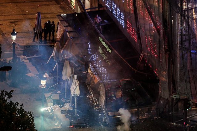This picture taken from the top of the Arch of Triumph (Arc de Triomphe) on July 15, 2018 shows police forces standing by the Drugstore Publicis building after it partially collapse while people celebrate the Russia 2018 World Cup final football match between France and Croatia, on the Champs-Elysees avenue in Paris. / AFP PHOTO / Ludovic MARIN
