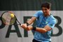Brazils Thomaz Bellucci plays a backhand return to Argentinas Federico Delbonis during their mens singles first round match on day one of The Roland Garros 2018 French Open tennis tournament in Paris on May 27, 2018. / AFP PHOTO / CHRISTOPHE SIMON