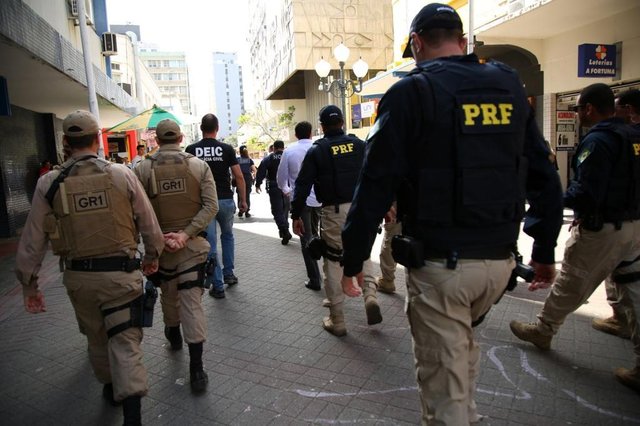 Uma operação integrada envolvendo mais de 100 agentes dos órgãos Federal, Estadual e Municipal resultou na fiscalização e apreensão de produtos ilegais que estavam sendo comercializados em galerias no Centro de Florianópolis. Cerca de 10 mil produtos entre roupas, sapatos e eletrônicos irregulares foram encontrados na tarde desta terça-feira (30), em três galerias, uma na Álvaro de Carvalho, outra na Rua Conselheiro Mafra e uma terceira Rua Deodoro. Conforme divulgação da CDL de Florianópolis, a loja da Deodoro foi interditada ¿devido à quantidade de produtos irregulares¿, com fiscais ficando no local para impedir o acesso no local. Nesta quarta-feira, 31 de outubro, o trabalho de recolhimento segue no local. Uma operação integrada envolvendo mais de 100 agentes dos órgãos Federal, Estadual e Municipal resultou na fiscalização e apreensão de produtos ilegais que estavam sendo comercializados em galerias no Centro de Florianópolis. Cerca de 10 mil produtos entre roupas, sapatos e eletrônicos irregulares foram encontrados na tarde desta terça-feira (30), em três galerias, uma na Álvaro de Carvalho, outra na Rua Conselheiro Mafra e uma terceira Rua Deodoro. Conforme divulgação da CDL de Florianópolis, a loja da Deodoro foi interditada ¿devido à quantidade de produtos irregulares¿, com fiscais ficando no local para impedir o acesso no local. Nesta quarta-feira, 31 de outubro, o trabalho de recolhimento segue no local.