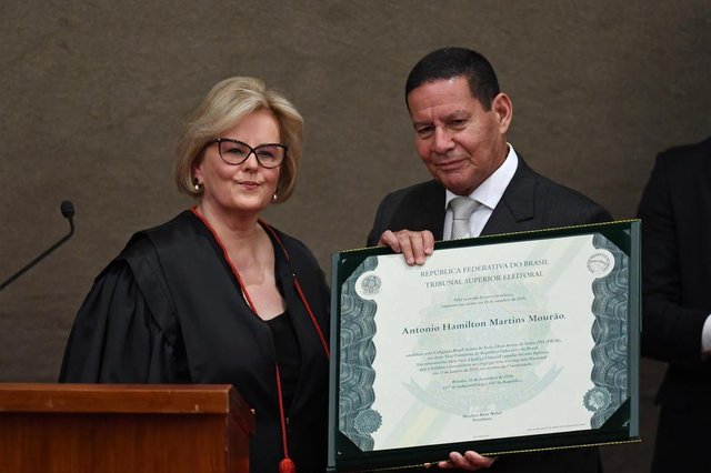 Brazilian Vice-President-elect Hamilton Mourao displays a diploma that certifies he can take office as vice-president, next to Electoral Supreme Court (TSE) president Justice Rosa Weber, during a ceremony at the TSE in Brasilia, on December 10, 2018. - Bolsonaro and his government take office on January 1, 2019. (Photo by EVARISTO SA / AFP)