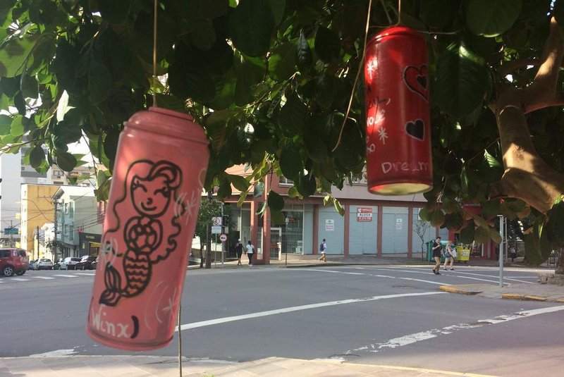 Alunos do Studio Santa Lata pintam latas das sobras de grafite, escrevem manifesto poético e as penduram em árvores no cntro de Caxias do Sul, na rua Maruês do Herval e Praça Dante. É o projeto Latas Poéticas.