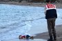 TOPSHOTSGRAPHIC CONTENTA Turkish police officer stands next to a migrant childs dead body off the shores in Bodrum, southern Turkey, on September 2, 2015 after a boat carrying refugees sank while reaching the Greek island of Kos. Thousands of refugees and migrants arrived in Athens on September 2, as Greek ministers held talks on the crisis, with Europe struggling to cope with the huge influx fleeing war and repression in the Middle East and Africa. AFP PHOTO / DOGAN NEWS AGENCY= TURKEY OUT =