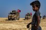 A Syrian boy watches as Turkish military vehicles, part of a US military convoy, take part in joint patrol in the Syrian village of al-Hashisha on the outskirts of Tal Abyad town along the border with Turkey, on October 4, 2019. - The United States and Turkey began joint patrols in northeastern Syria aimed at easing tensions between Ankara and US-backed Kurdish forces. (Photo by Delil SOULEIMAN / AFP)