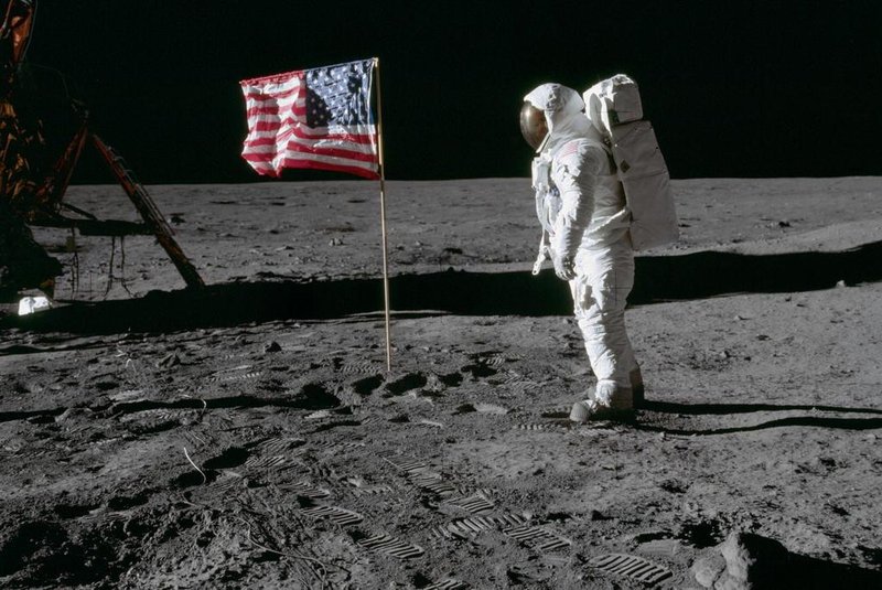 AS11-40-5875 (20 July 1969) --- Astronaut Edwin E. Aldrin Jr., lunar module pilot of the first lunar landing mission, poses for a photograph beside the deployed United States flag during an Apollo 11 extravehicular activity (EVA) on the lunar surface. The Lunar Module (LM) is on the left, and the footprints of the astronauts are clearly visible in the soil of the moon. Astronaut Neil A. Armstrong, commander, took this picture with a 70mm Hasselblad lunar surface camera. While astronauts Armstrong and Aldrin descended in the LM, the Eagle, to explore the Sea of Tranquility region of the moon, astronaut Michael Collins, command module pilot, remained with the Command and Service Modules (CSM) Columbia in lunar orbit. Photo credit: NASAO astronauta Edwin E. Aldrin Jr., piloto do módulo lunar da primeira missão de pouso lunar, posa para uma fotografia ao lado da bandeira dos Estados Unidos durante uma atividade extraveicular da Apollo 11 (EVA) na superfície lunar.APOLLO 11 ONBOARD PHOTO: GOOD VIEW OF ASTRONAUT FOOTPRINT IN LUNAR SOIL.