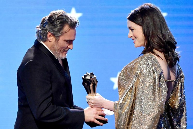SANTA MONICA, CALIFORNIA - JANUARY 12: (L-R) Joaquin Phoenix accepts the Best Actor award for Joker from Anne Hathaway onstage during the 25th Annual Critics Choice Awards at Barker Hangar on January 12, 2020 in Santa Monica, California.   Amy Sussman/Getty Images/AFP<!-- NICAID(14385025) -->