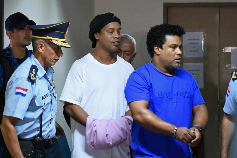  Brazilian retired football player Ronaldinho (C) and his brother Roberto Assis (R) arrive at Asuncions Justice Palace to appear before a public prosecutor who will decide whether to grant them bail or not following their irregular entry to the country, in Asuncion, on March 7, 2020. - Former Brazilian football star Ronaldinho and his brother have been detained in Paraguay after allegedly using fake passports to enter the South American country, authorities said Wednesday. (Photo by Norberto DUARTE / AFP)Editoria: CLJLocal: AsuncionIndexador: NORBERTO DUARTESecao: soccerFonte: AFPFotógrafo: STR<!-- NICAID(14445407) -->