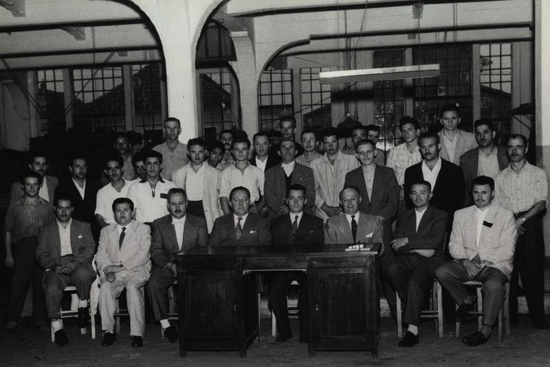 Graciano Fillippini ladeado pelos diretores Júlio João Eberle (E) e Caetano Pettinelli, durante o seu jubileu de prata na empresa, em 21 de janeiro de 1957. À primeira fila estão, entre outros, Humberto Bassanesi e Alcides Fedrizzi.<!-- NICAID(14575992) -->