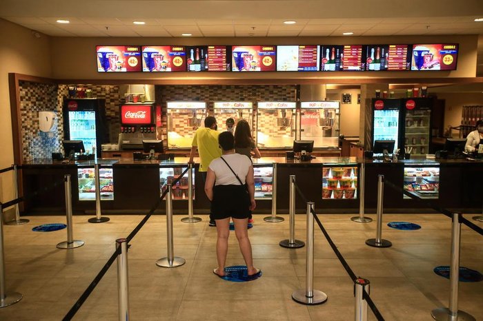 Adesivos no chão indicam distância entre as pessoas na fila