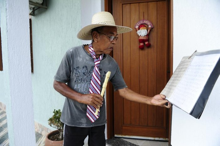 Partituras escritas a mão, em uma folha pautada, estão apoiadas sobre o pedestal