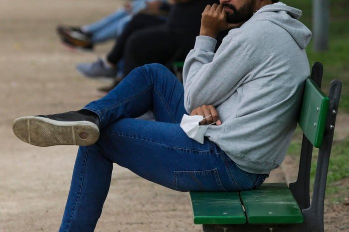 Pessoas sentadas nos bancos contrariam as regras instituídas no último decreto