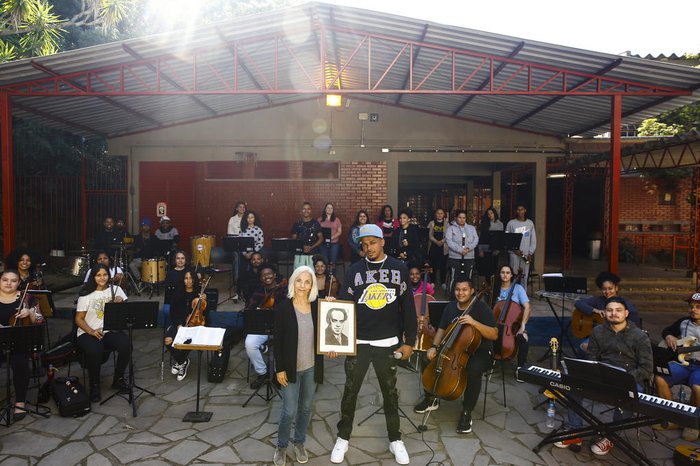 Cecília (a frente, de cabelos brancos) e Preto X (a frente, de boné) seguram imagem de Heitor Villa-Lobos