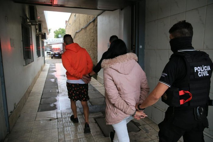 Duas pessoas sendo conduzidas pelos policiais