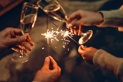 Happy New Year and Merry Christmas! Glasses with champagne in hand and sparklers.Fonte: 299891577<!-- NICAID(15620399) -->