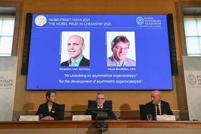 (Bottom L-R) Member of the Nobel Committee for Chemistry Pernilla Wittung Stafshede, Goran K Hansson, Secretary General of the Royal Swedish Academy of Sciences and member of the Nobel Committee for Chemistry Peter Somfai address a press conference to announce the winners of the 2021 Nobel Prize in Chemistry (On display L-R) Germany's Benjamin List and David MacMillan of the United States, at the Royal Swedish Academy of Sciences in Stockholm, Sweden, on October 6, 2021. - Germany's Benjamin List and David MacMillan of the United States on October 6, 2021 won the Nobel Prize in Chemistry for their development of a precise new tool for molecular construction, the jury said. The duo was awarded "for their development of a precise new tool for molecular construction: organocatalysis. This has had a great impact on pharmaceutical research, and has made chemistry greener," the Nobel Committee said. (Photo by Jonathan NACKSTRAND / AFP)Editoria: HUMLocal: StockholmIndexador: JONATHAN NACKSTRANDSecao: chemistryFonte: AFPFotógrafo: STR<!-- NICAID(14907535) -->