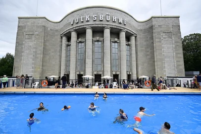 (FILES) Visitors swim in the so-called "Volksbad" swimming pool set up in front of the Volksbuehne theatre at Rosa-Luxemburg-Platz square in Berlin on August 7, 2026, on the day of its opening. The Volksbuehne scrapped plans on August 14, 2026 to reserve the pool for black children and young people for one afternoon, citing a backlash and security fears sparked by "racist agitation". The Volksbuehne theatre and the anti-racism organisation Each One Teach One (EOTO) had intended the event, for black "children, young people and their relatives", as "a positive measure to support structurally disadvantaged groups". However, they said this had sparked inflammatory media coverage as well as racist emails and threats of violence that had raised safety concerns. (Photo by John MACDOUGALL / AFP)<!-- NICAID(16347553) -->