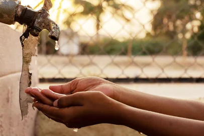 Closeup of hands, child drinking water directly from corporation tap water in IndiaFalta de água. Foto: WESTOCK  / stock.adobe.comFonte: 257865836<!-- NICAID(15479131) -->
