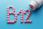 Pink round vitamins B12 shaped pills on a blue background spilled from a white canVitamina B12 - Foto: Alexander/stock.adobe.comIndexador: Aleksandr GrechanyukFonte: 269052122<!-- NICAID(15341316) -->