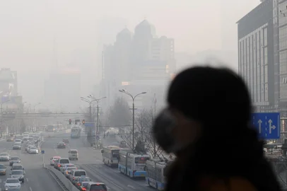 A woman wearing a face mask walks on an overpass in Beijing on January 16, 2014.  China's capital was shrouded in thick smog on January 16, cutting visibility down to a few hundred metres as a count of small particulate pollution reached more than 20 times recommended levels.        AFP PHOTO / WANG ZHAO<!-- NICAID(10149074) -->
