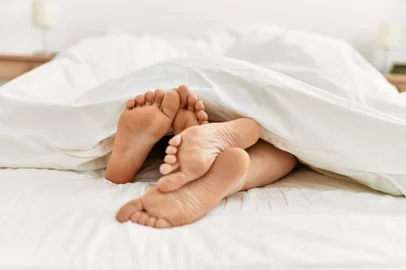 Couple feet under sheets on the bed at home.Casal na cama - Foto: Krakenimages.com/stock.adobe.comFonte: 451068984<!-- NICAID(15704480) -->