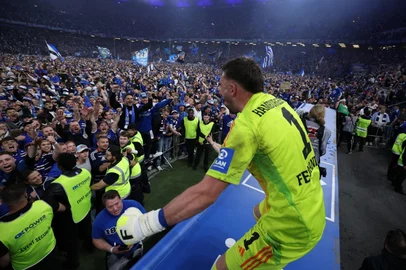 Hamburg's players including German goalkeeper #01 Daniel Heuer Fernandes celebrate with their fans who invaded the pitch after the final whistle of the German second division Bundesliga football match between Hamburg SV and SSV Ulm 1846 in Hamburg, northern Germany on May 10, 2025. Hamburg SV will return to play in the first division next season. (Photo by RONNY HARTMANN / AFP) / DFL REGULATIONS PROHIBIT ANY USE OF PHOTOGRAPHS AS IMAGE SEQUENCES AND/OR QUASI-VIDEO<!-- NICAID(16034592) -->