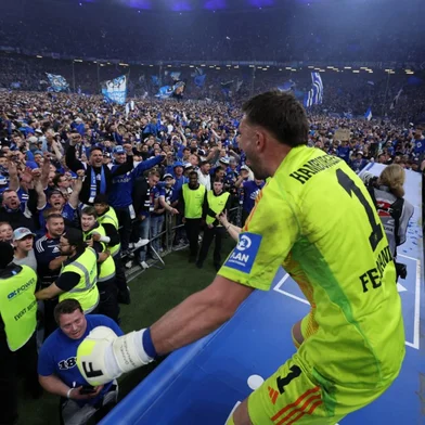 Hamburg's players including German goalkeeper #01 Daniel Heuer Fernandes celebrate with their fans who invaded the pitch after the final whistle of the German second division Bundesliga football match between Hamburg SV and SSV Ulm 1846 in Hamburg, northern Germany on May 10, 2025. Hamburg SV will return to play in the first division next season. (Photo by RONNY HARTMANN / AFP) / DFL REGULATIONS PROHIBIT ANY USE OF PHOTOGRAPHS AS IMAGE SEQUENCES AND/OR QUASI-VIDEO<!-- NICAID(16034592) -->