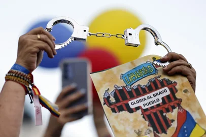 A demonstrator holds a pair of handcuffs and a sign reading "Freedom. Glory to the brave people" during a protest against Venezuelan President Nicolas Maduro's disputed victory in Venezuela's Presidential elections, at Puerta del Sol, Madrid, on August 3, 2024. (Photo by OSCAR DEL POZO / AFP)<!-- NICAID(15832051) -->