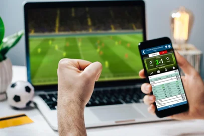 Man watching football play online broadcast on his laptop, cheering for his favorite team and making bets at bookmaker's websiteLucky man celebrating money win. Male fan watching football play online broadcast on his laptop, cheering for his favorite team and making bets at bookmaker's website.Indexador: WpadingtonFonte: 305724983<!-- NICAID(15888795) -->