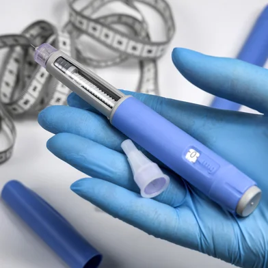 Hands in surgical gloves holding Ozempic Insulin injection pen for diabetics.Hands in blue surgical gloves holding Ozempic Insulin injection pen for diabetics. Fonte: 726555519<!-- NICAID(16302717) -->