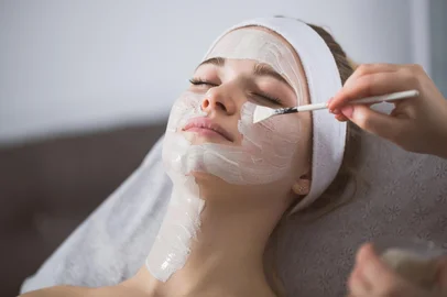 Beautician applying anzymatic peeling on woman's face in spa<!-- NICAID(15992396) -->
