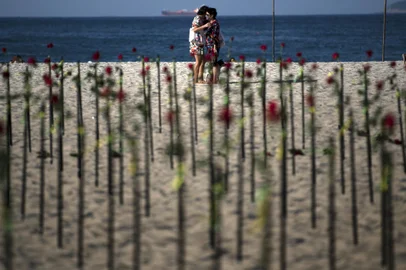 People hug behind roses placed by the NGO Rio de Paz on Copacabana beach, Rio de Janeiro, in memory of Brazil's half a million COVID-19 victims, on June 20, 2021. - On the eve, Brazil became the second country after the United States to surpass 500,000 Covid-19 deaths as the South American giant grapples with a third wave of the pandemic. (Photo by CARL DE SOUZA / AFP)Editoria: HTHLocal: Rio de JaneiroIndexador: CARL DE SOUZASecao: diseaseFonte: AFPFotógrafo: STF<!-- NICAID(14813460) -->