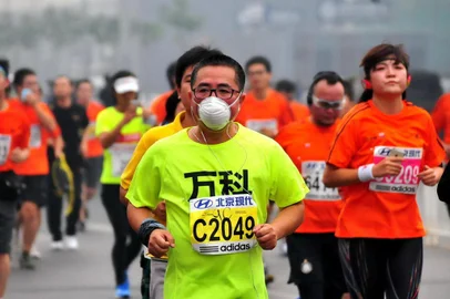 A runner wears a mask as he takes part in the 34th Beijing International Marathon which began at Tiananmen Square in Beijing on October 19, 2014, with many of the tens of thousands of participants wearing face masks, as the 42-kilometer course ended at the Olympic Park.          CHINA OUT         AFP PHOTO<!-- NICAID(10917584) -->