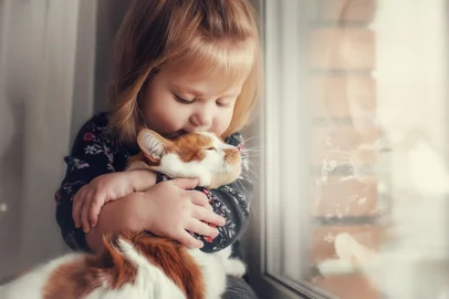 Criança abraçada em um gato.*Fonte: 203294053<!-- NICAID(15747573) -->