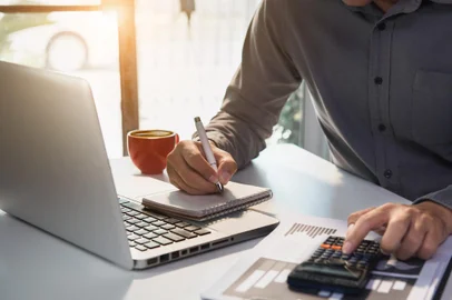 Male businessman working on desk office with using a calculator to calculate the numbers, finance accounting concept.Fonte: 294105357<!-- NICAID(14530970) -->