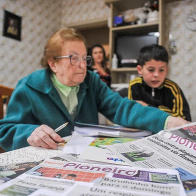 CAXIAS DO SUL, RS, BRASIL, 12/09/2023. Professora aposentada alfabetiza menino que teve o aprendizado prejudicado durante a pandemia de covid-19. Na foto, Eolina Kayser, 88, Leonardo Drum, 10 e ao fundo Solange Santos Imer (Neimar De Cesero/Agência RBS).Indexador: NEIMAR DE CESERO<!-- NICAID(15538133) -->
