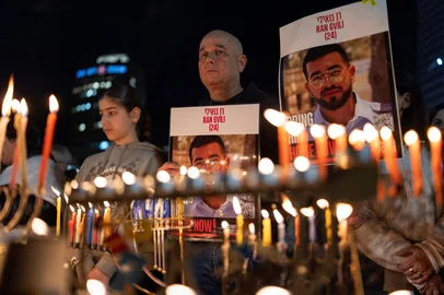 (FILES) Israelis light the 8th candle of Hannukah in Hostage Square holding placards bearing the face of Ran Gvili in Tel Aviv on December 21, 2025, as they call for the return of his remains. Israeli forces were searching a cemetery in the Gaza Strip for the remains of Ran Gvili, the last hostage still held in the Palestinian territory, the Israeli Prime Minister Benjamin Netanyahu's office said on Januray 25, 2026. The announcement came shortly after Hamas's armed wing said in a statement that it had provided information on the location of the slain police officer's body. (Photo by ILIA YEFIMOVICH / AFP)<!-- NICAID(16211623) -->