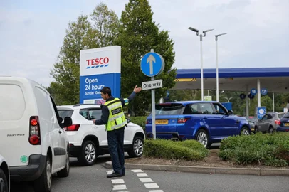 A security guard assists drivers queuing to fill up at a Tesco petrol station in Camberley, west of London on September 26, 2021. - Britain's transport secretary Grant Shapps on Sunday accused lorry industry representatives of helping to spark petrol panic-buying, as he defended a U-turn on post-Brexit immigration policy to ease an escalating supply crisis. (Photo by Adrian DENNIS / AFP)<!-- NICAID(14900964) -->