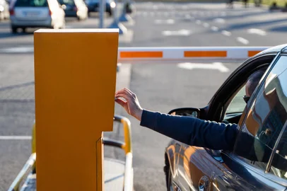 Person in the car inserting into or removing ticket from parking vending machine. Paying, entering parking lot or exiting garage concept. Daytime setting.Entrada de estacionamento - Foto: Volodymyr/stock.adobe.comFonte: 342689060<!-- NICAID(15744276) -->