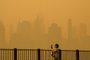 A person wearing a face mask takes photos of the skyline as smoke from wildfires in Canada cause hazy conditions in New York City on June 7, 2023. An orange-tinged smog caused by Canada's wildfires shrouded New York on Wednesday, obscuring its famous skyscrapers and causing residents to don face masks, as cities along the US East Coast issued air quality alerts. (Photo by ANGELA WEISS / AFP)Editoria: DISLocal: New YorkIndexador: ANGELA WEISSSecao: environmental pollutionFonte: AFPFotógrafo: STF<!-- NICAID(15451364) -->