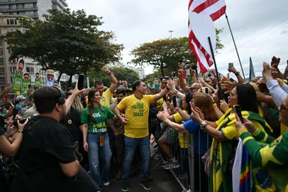 MAURO PIMENTEL / AFP Brazil's right-wing presidential candidate and senator Flavio Bolsonaro greets supporters next to his wife Fernanda, on arrival at a campaign rally at Copacaban beach in Rio de Janeiro, Brazil, on August 16, 2026. Brazilians will go to the polls next October 4 once again deeply polarized and under the shadow of U.S. President Donald Trump, who has backed conservative candidates in recent elections in Latin America. (Photo by MAURO PIMENTEL / AFP)<!-- NICAID(16346707) -->
