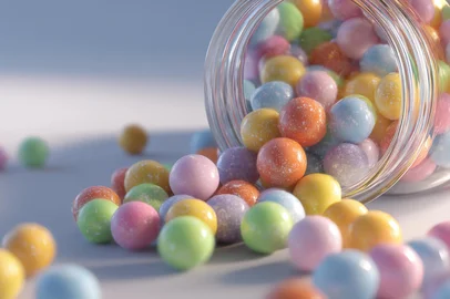 An enticing still life featuring a jar of pastel colored candies with a soft focus, spilling onto a white surface, creating a sweet and playful visual appeal.Fonte: 1449846964<!-- NICAID(16030962) -->