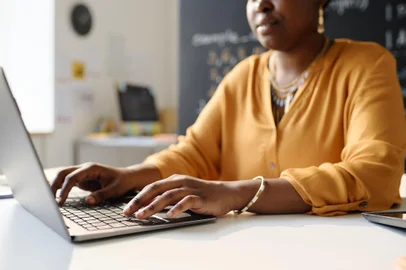 Teacher working on laptop at schoolClose-up of African American teacher working on laptop at schoolFonte: 622274653<!-- NICAID(15648444) -->
